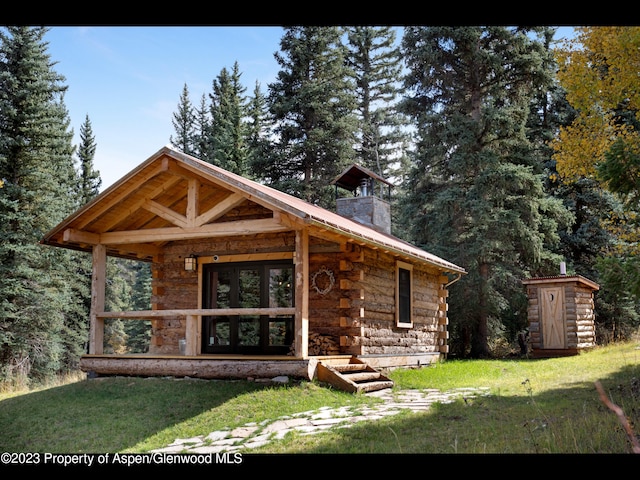 log-style house featuring a front lawn and an outdoor structure