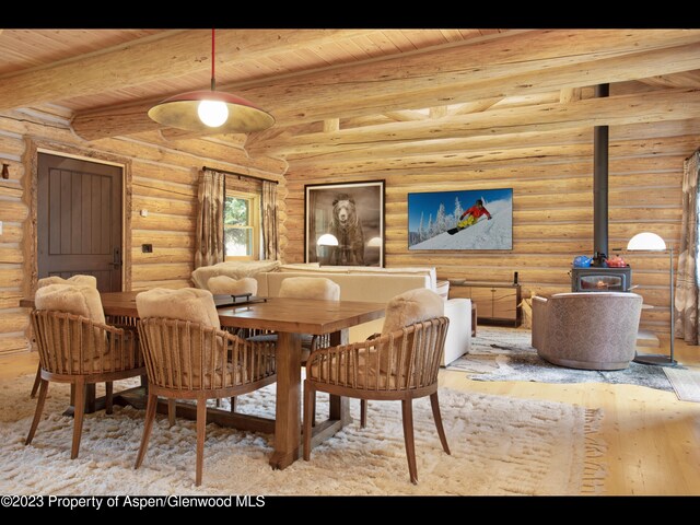 dining space featuring wood ceiling, rustic walls, beamed ceiling, and light hardwood / wood-style floors