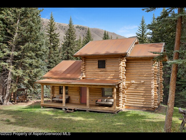 back of property with a mountain view and a lawn