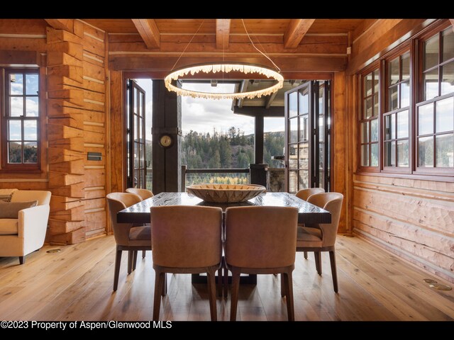 dining room featuring beamed ceiling, wood walls, and wooden ceiling