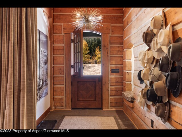 foyer entrance featuring wooden walls and a notable chandelier