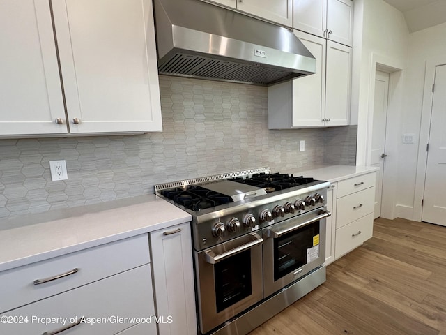 kitchen featuring decorative backsplash, light hardwood / wood-style flooring, white cabinets, and range with two ovens