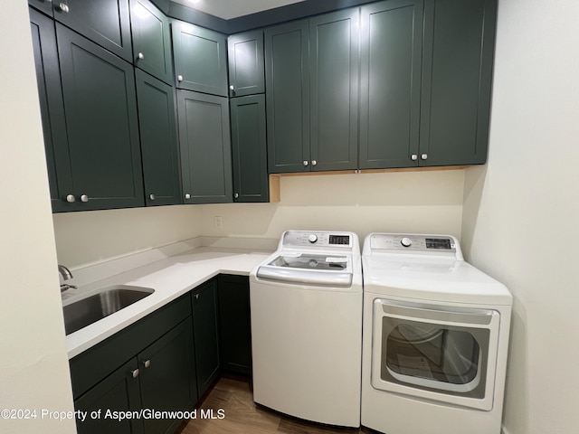 laundry room featuring cabinets, washer and clothes dryer, dark wood-type flooring, and sink