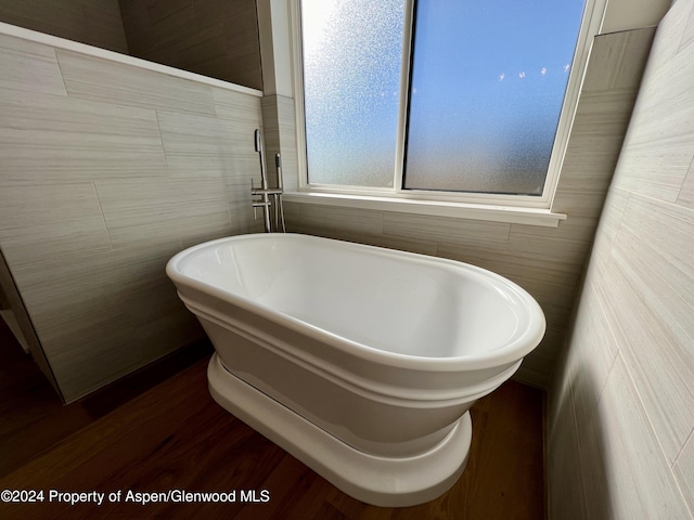 bathroom with a washtub and wood-type flooring