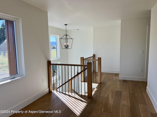 stairway with hardwood / wood-style flooring and a notable chandelier