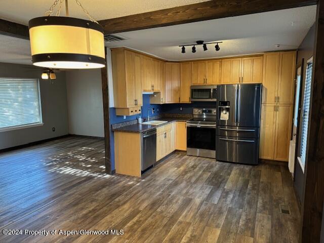 kitchen featuring beam ceiling, dark hardwood / wood-style floors, and appliances with stainless steel finishes