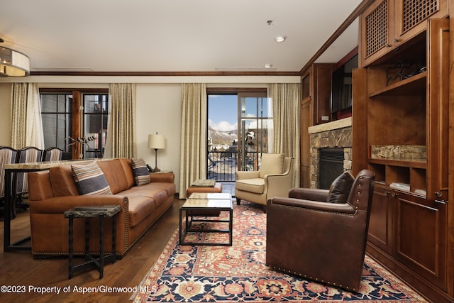 living room with a stone fireplace, crown molding, and dark hardwood / wood-style flooring