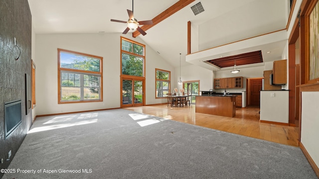 148 Laird Ln, Glenwood Springs, CO 81601 - unfurnished living room featuring high vaulted ceiling, light colored carpet, ceiling fan, a tile fireplace, and beamed ceiling