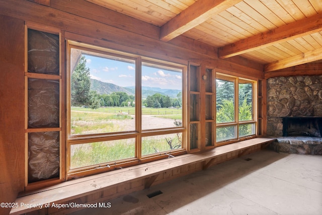 176 Letey Ln, Woody Creek, CO 81656 - unfurnished living room with a mountain view, healthy amount of natural light, a wood ceiling with exposed beams, and a stone fireplace