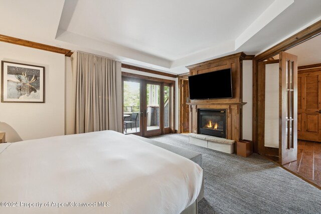 bedroom featuring access to outside, a raised ceiling, and french doors