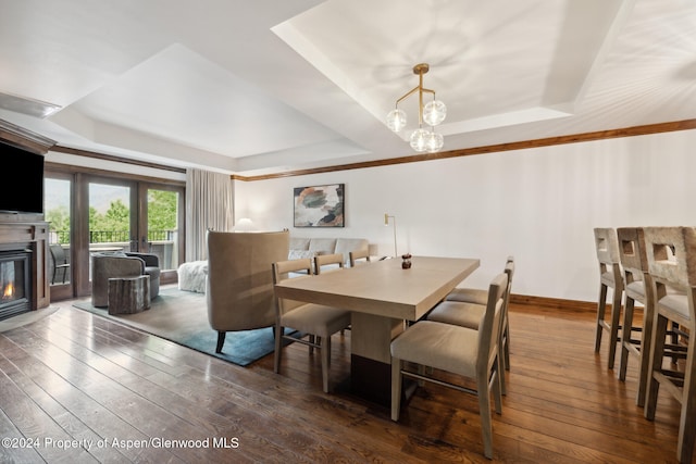 dining room featuring a tray ceiling, dark wood-type flooring, and a notable chandelier