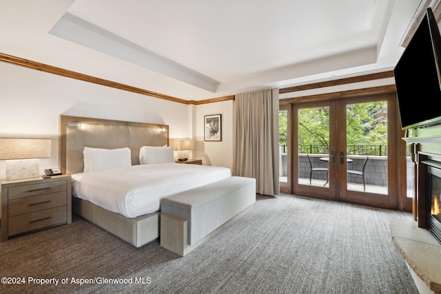 carpeted bedroom with access to exterior, french doors, and a tray ceiling