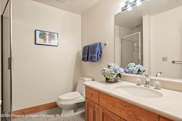 bathroom with vanity, toilet, and a shower with door