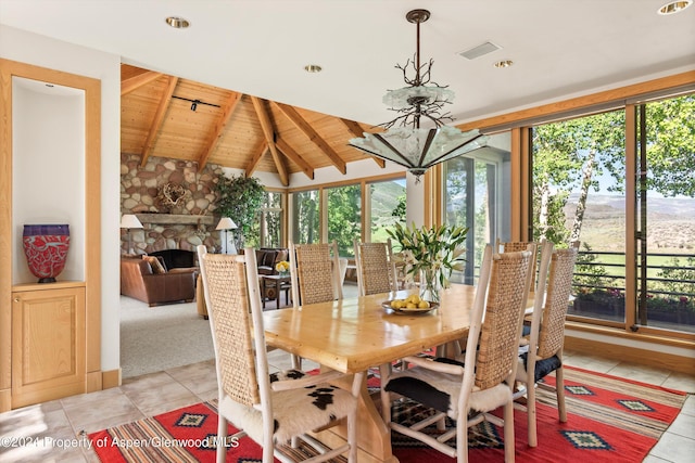 tiled dining area featuring lofted ceiling with beams, a healthy amount of sunlight, a fireplace, and wood ceiling