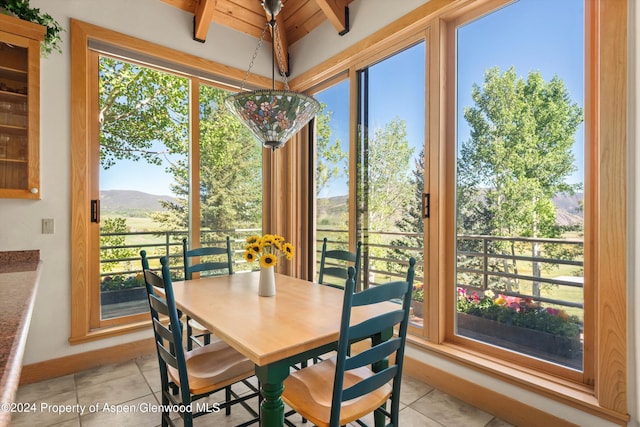 dining area featuring a mountain view, light tile patterned flooring, plenty of natural light, and wood ceiling