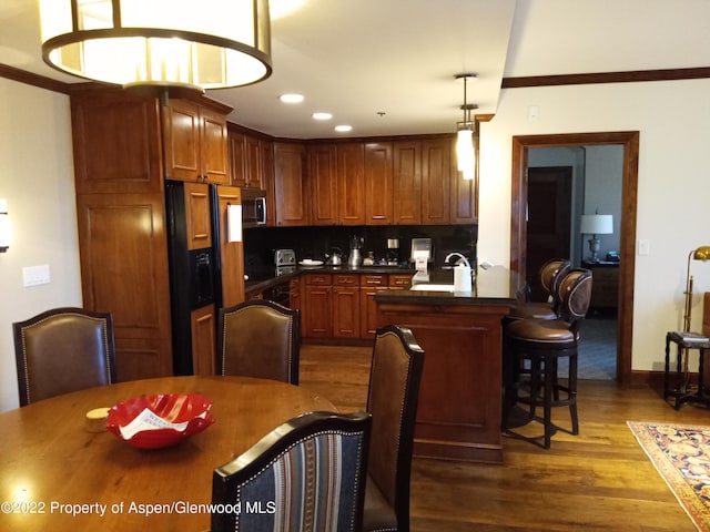 kitchen featuring sink, hanging light fixtures, dark hardwood / wood-style floors, crown molding, and fridge