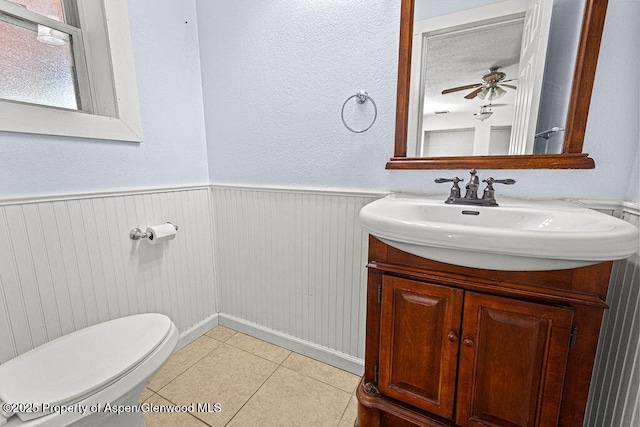 648 Colorado St, Craig, CO 81625 - bathroom featuring vanity, toilet, tile patterned floors, ceiling fan, and a wainscoted wall