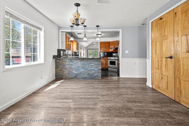 648 Colorado St, Craig, CO 81625 - kitchen with stainless steel range with gas cooktop, dark countertops, a chandelier, dark wood finished floors, and brown cabinets