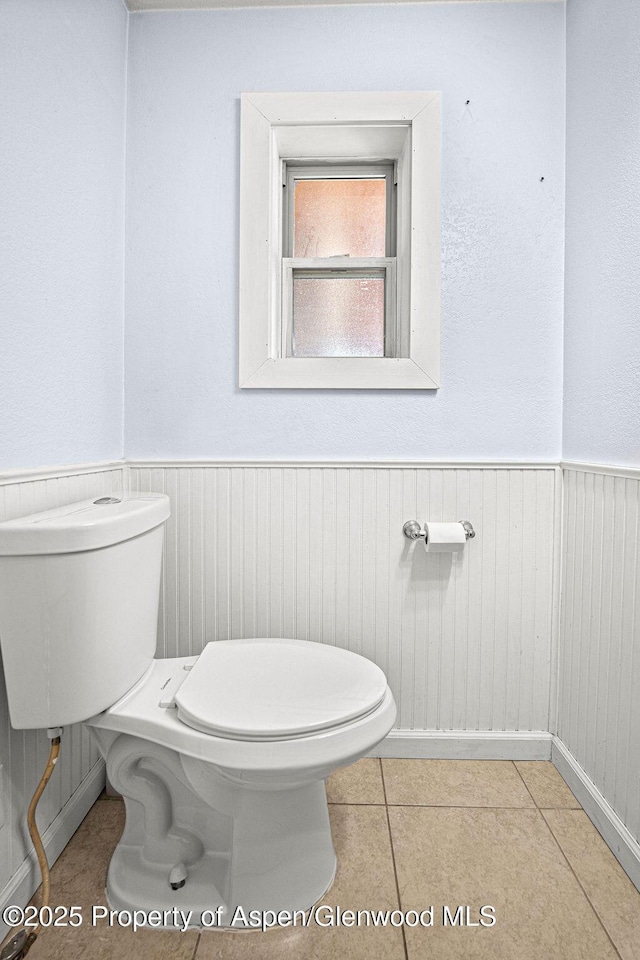 648 Colorado St, Craig, CO 81625 - bathroom featuring toilet, wainscoting, wooden walls, and tile patterned floors