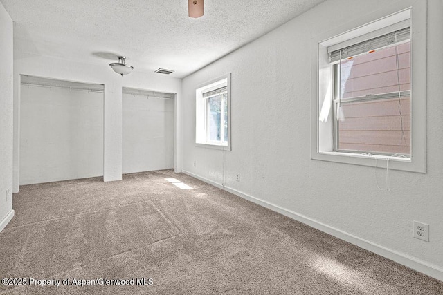 648 Colorado St, Craig, CO 81625 - unfurnished bedroom featuring two closets, a textured ceiling, carpet flooring, a textured wall, and baseboards