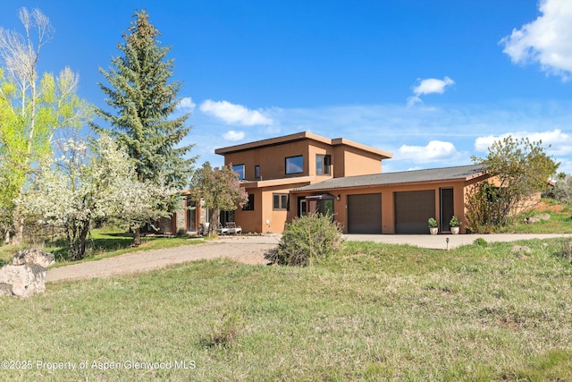 214 Prince Dr, Carbondale, CO 81623 - view of front of house featuring a garage, driveway, a front yard, and stucco siding