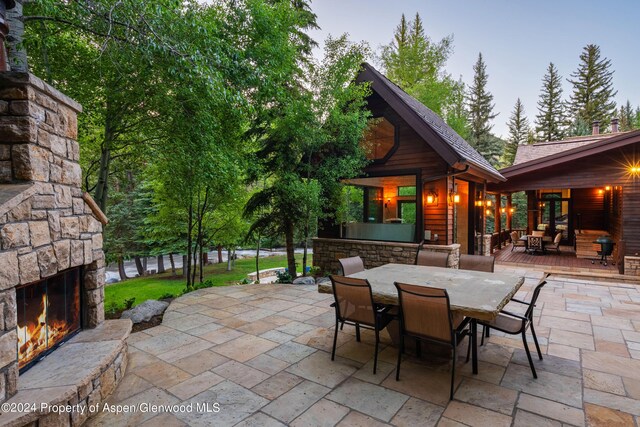 patio terrace at dusk featuring an outdoor stone fireplace