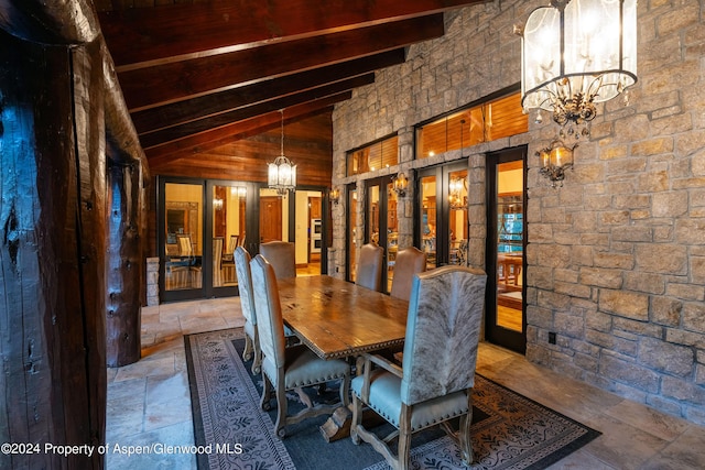 dining room with french doors, beamed ceiling, high vaulted ceiling, a notable chandelier, and wooden walls