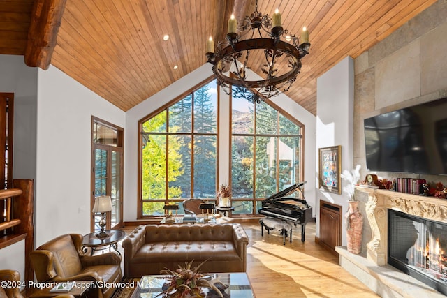 living room featuring high vaulted ceiling, an inviting chandelier, light hardwood / wood-style flooring, a premium fireplace, and wood ceiling