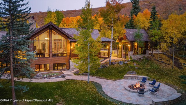 rear view of house with a mountain view, a patio, a fire pit, and a lawn