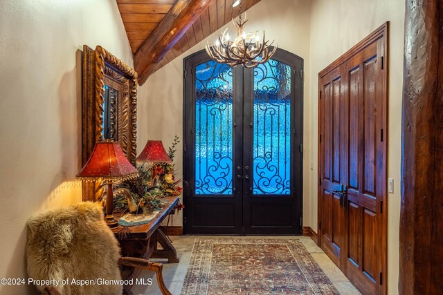 foyer entrance with french doors, lofted ceiling with beams, an inviting chandelier, and wood ceiling