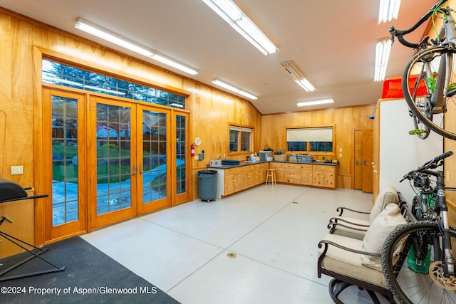 kitchen featuring french doors, lofted ceiling, and wood walls