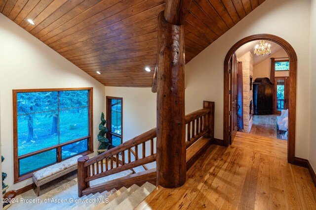 hallway featuring a notable chandelier, lofted ceiling, light wood-type flooring, and wood ceiling