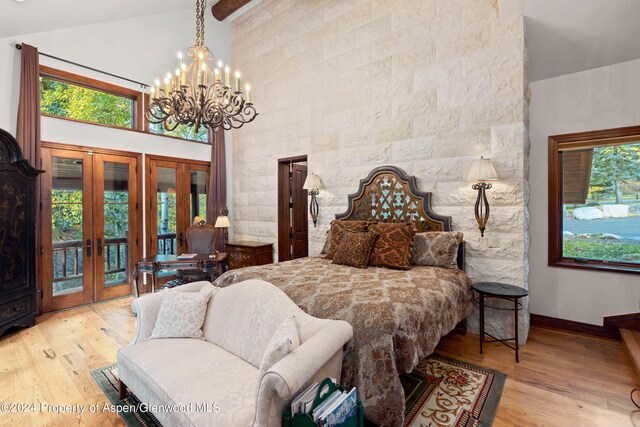 bedroom with a notable chandelier, light hardwood / wood-style floors, access to outside, and french doors