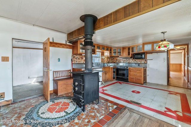 kitchen with dark countertops, electric stove, black microwave, glass insert cabinets, and a wood stove