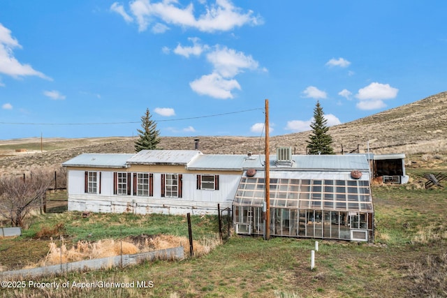 back of house featuring an exterior structure, an outdoor structure, metal roof, and a mountain view