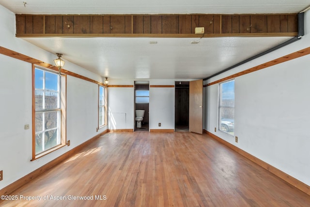 unfurnished living room with baseboards, a healthy amount of sunlight, and wood finished floors