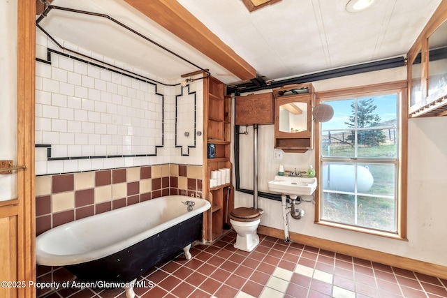 full bathroom with tile patterned flooring, a freestanding bath, toilet, a sink, and baseboards