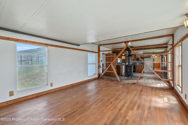 interior space featuring wood-type flooring, a wood stove, and baseboards