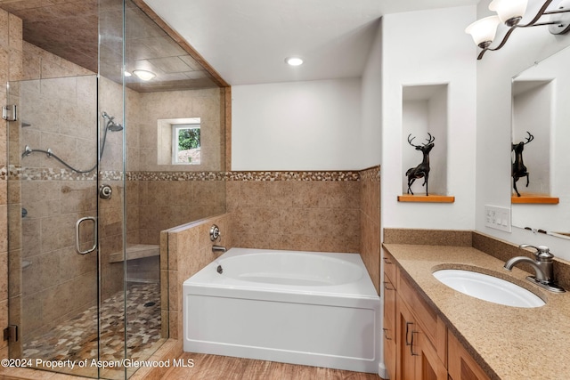 bathroom featuring vanity, plus walk in shower, and tile walls