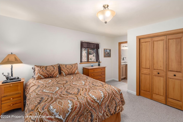 bedroom featuring ensuite bath and light colored carpet