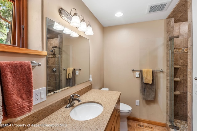 bathroom featuring vanity, toilet, and a shower with door