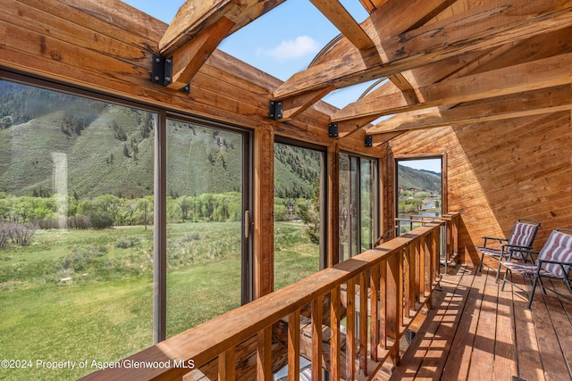 unfurnished sunroom featuring a mountain view and lofted ceiling with beams