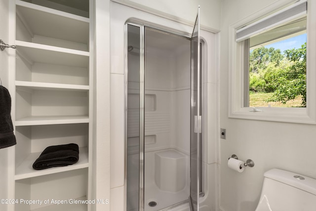 bathroom featuring toilet and a shower with shower door