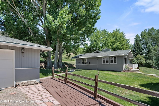 wooden deck with a garage and a lawn