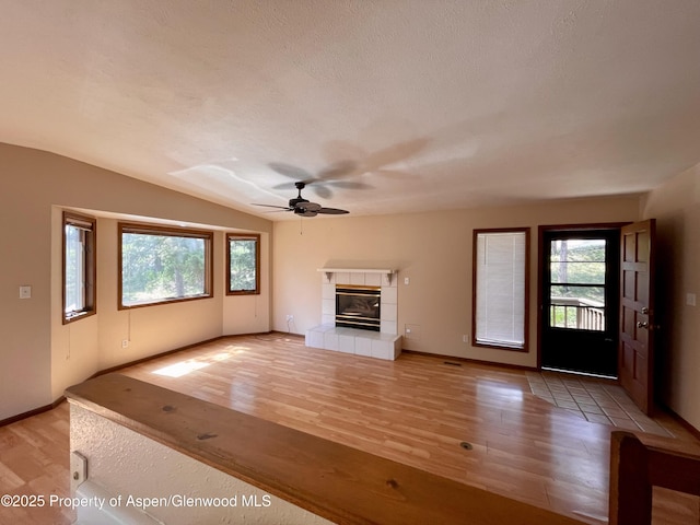 6616 High Dr, Morrison, CO 80465 - unfurnished living room featuring healthy amount of natural light, ceiling fan, light wood finished floors, a fireplace, and lofted ceiling