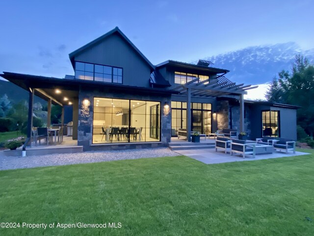 back house at dusk featuring a mountain view, a pergola, an outdoor hangout area, a yard, and a patio area