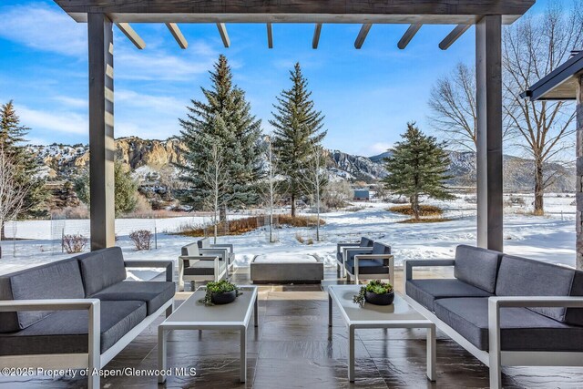 snow covered patio with a mountain view and an outdoor hangout area