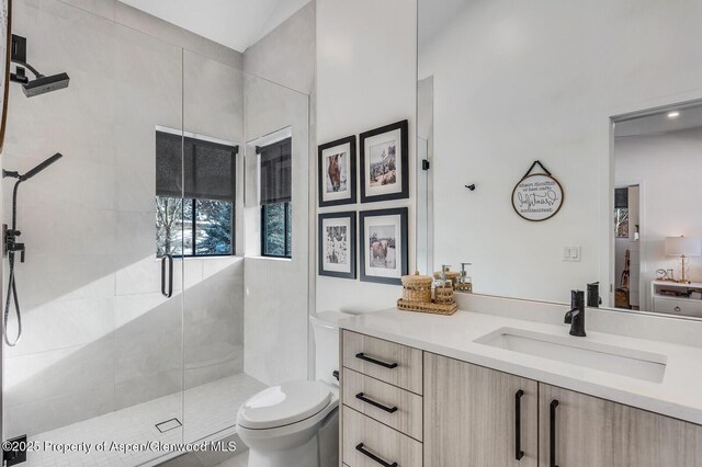 bathroom featuring toilet, vanity, and tiled shower