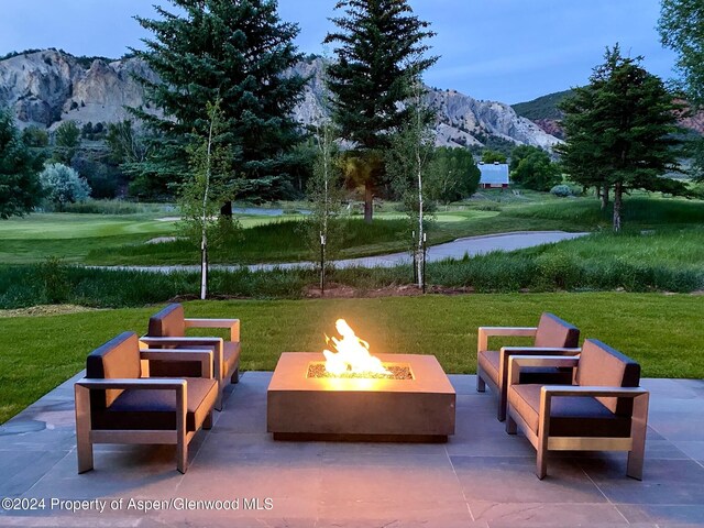 view of community with a mountain view, a yard, an outdoor fire pit, and a patio area