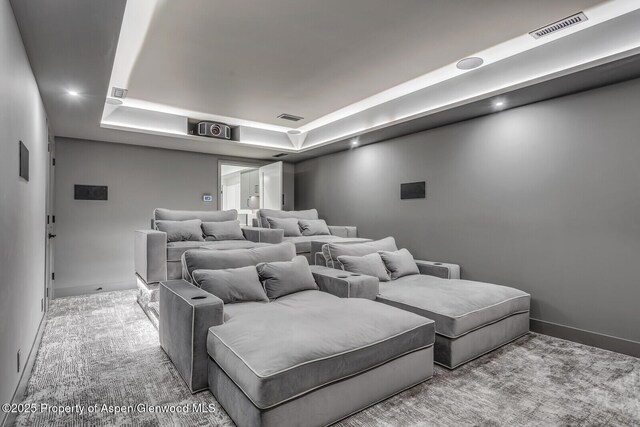 carpeted home theater with a raised ceiling